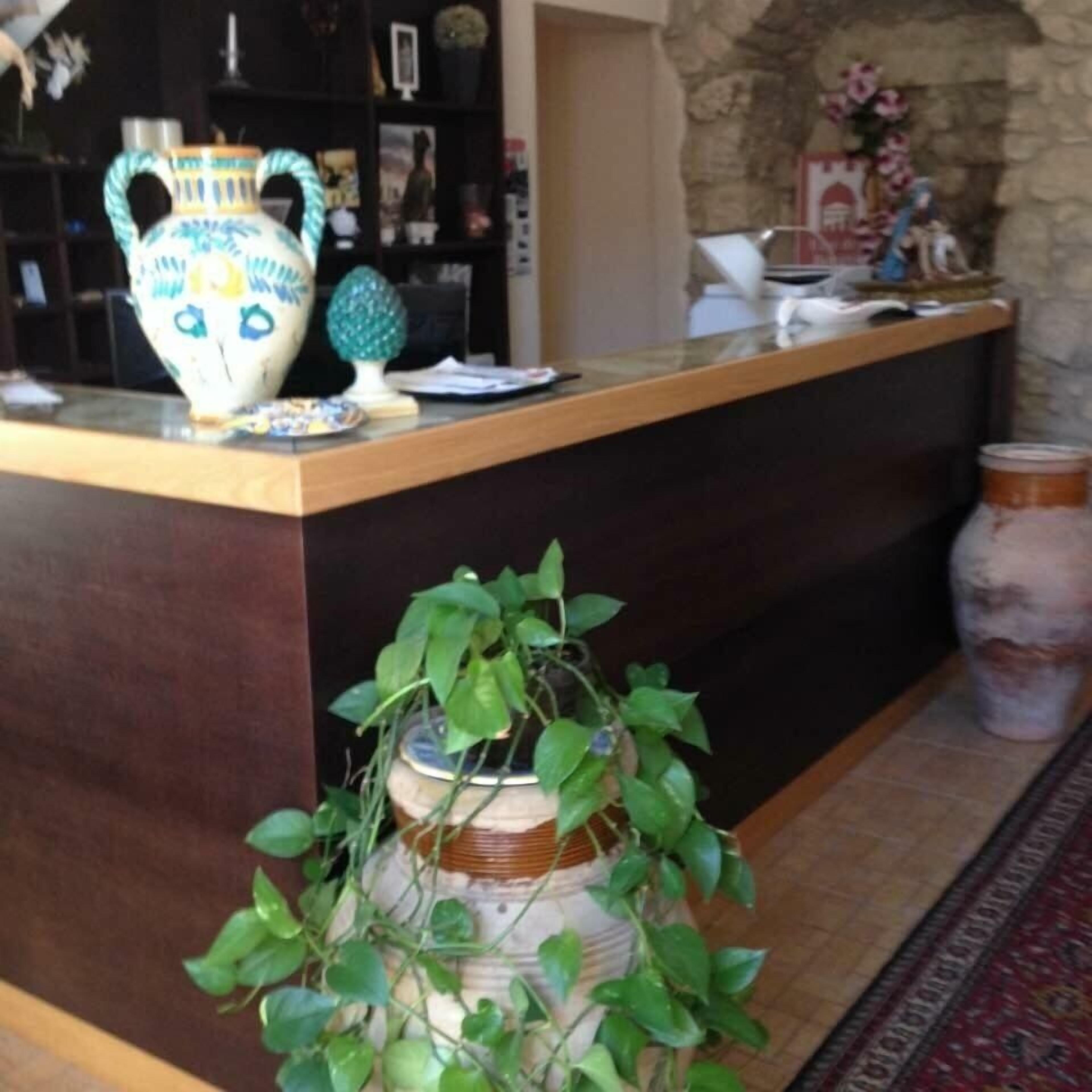 Un comptoir d’accueil orné d’un vase, d’une petite plante et d’un objet décoratif.