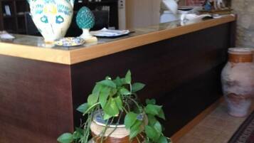 Un comptoir d’accueil orné d’un vase, d’une petite plante et d’un objet décoratif.
