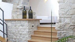 A stone archway leading to a staircase with wooden steps and a white wall in the background. - B&B Dinastia (Monterosso Almo)
