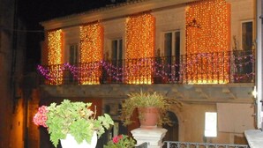 A building with balconies adorned with string lights and purple garlands. - B&B Dinastia (Monterosso Almo)