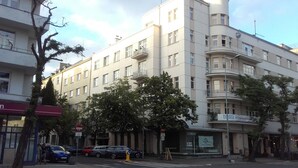 Un immeuble à plusieurs étages doté d’une façade plane, de balcons et d’une entrée au niveau du sol.