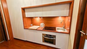 Eine kleine Küche mit weißen Schränken, einer Holz Arbeitsplatte, einem eingebauten Backofen und einem Spülbecken.