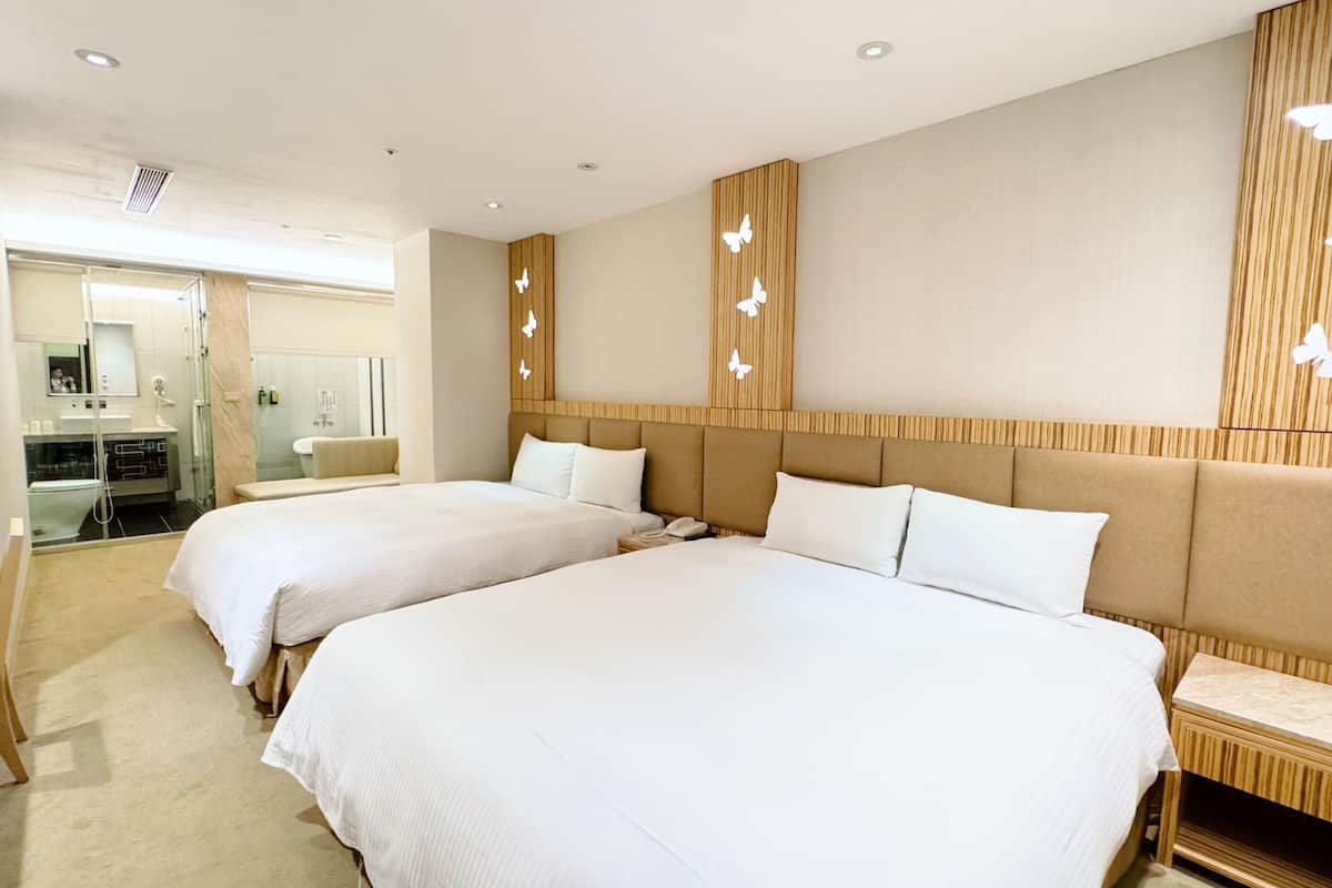 A hotel room with two beds, a wooden headboard, and a mirror.