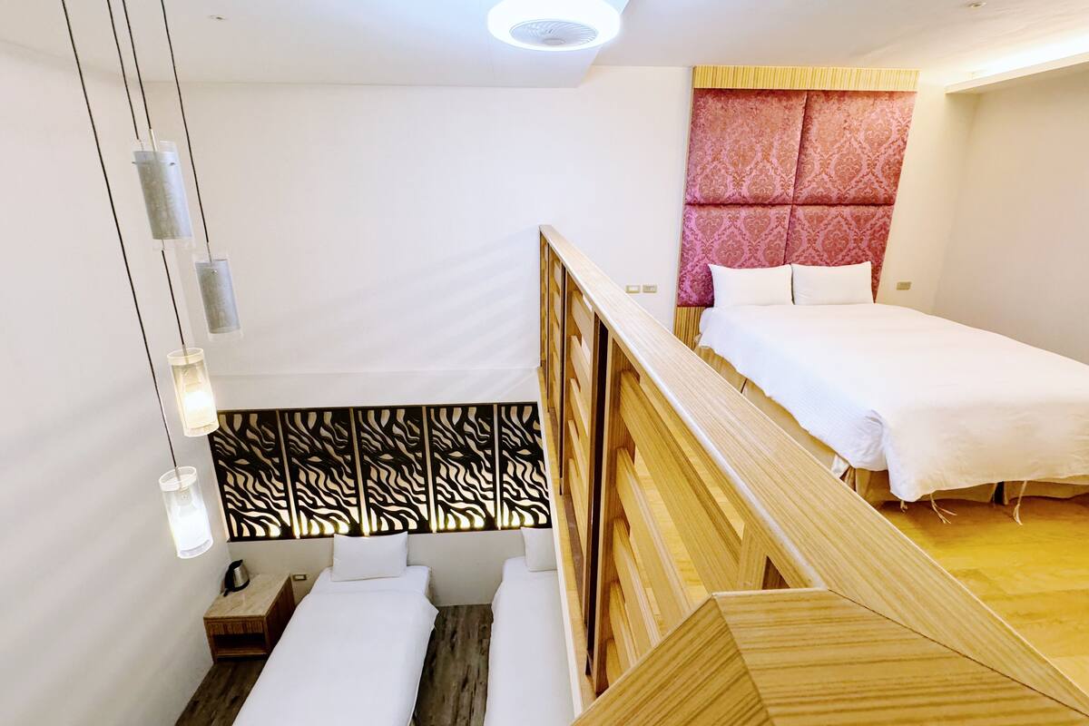 A modern hotel room with a wooden bunk bed, a small bedside table with a kettle, and a decorative headboard.