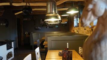 Ein Restaurantinneres mit Holzbalken, Pendelleuchten, einem Kamin und einem Menüständer.