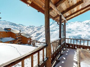 A wooden balcony with a view of snow-covered mountains.