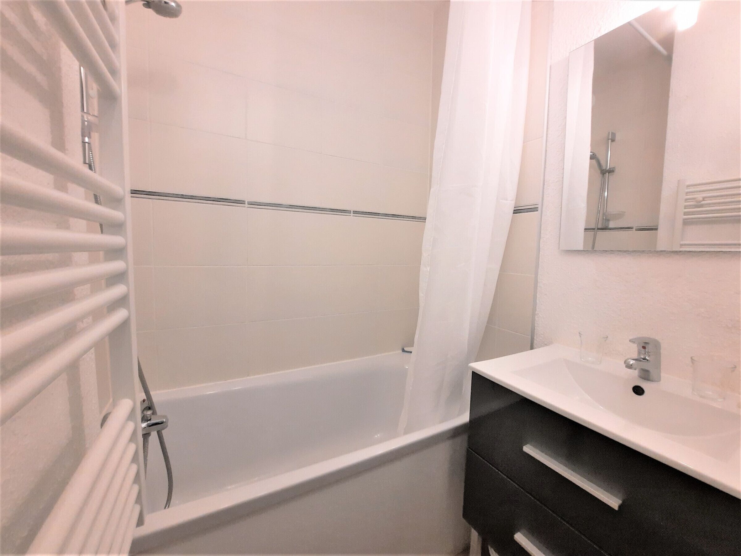 A bathroom with a bathtub, a shower, a sink, and a mirror.