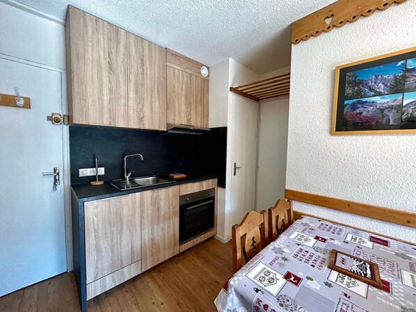 A compact kitchen with wooden cabinets, a black countertop, and a built-in oven.