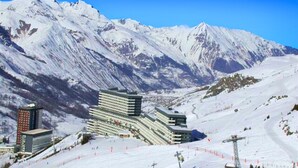 A hotel with multiple floors, ski slopes in the foreground, and snow-covered mountains in the background. - Ski-in equipped studio - Les Menuires (Les Menuires)