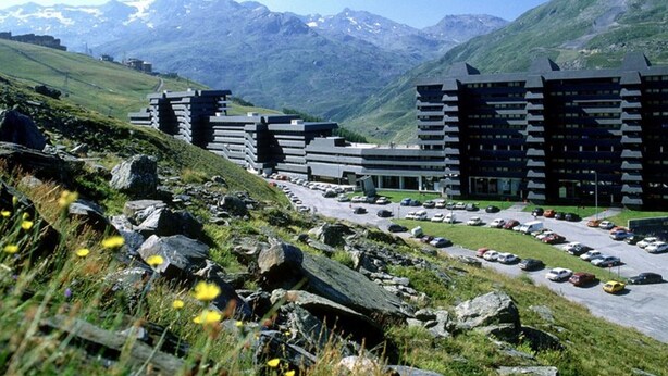 A modern hotel with multiple floors and a parking lot, surrounded by mountains and greenery. - Ski-in equipped studio - Les Menuires (Les Menuires)
