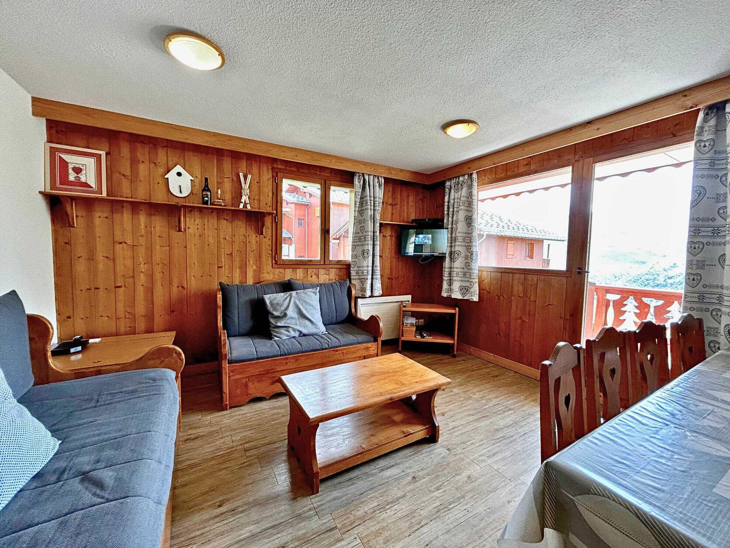 Ein gemütliches Holzhaus mit einer Couch, einem Holztisch und einem Fernseher in einer Ecke.