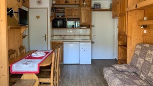 Une cuisine compacte avec des meubles en bois, un four à micro-ondes, un lave-vaisselle et un petit réfrigérateur.