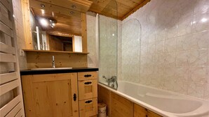 Un baño de madera con bañera, lavamanos y espejo.