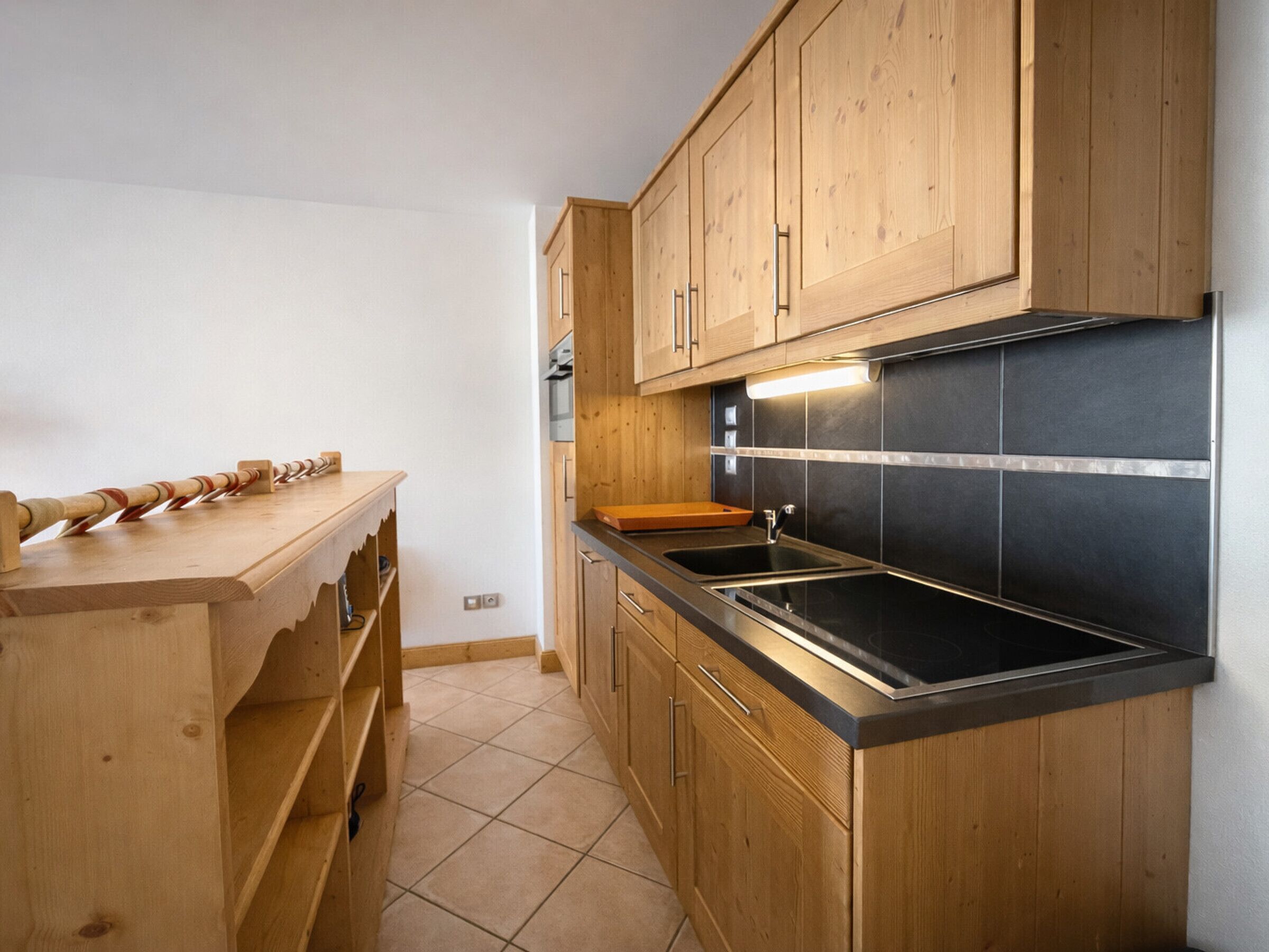 A kitchen with wooden cabinets, a black countertop, and a tiled backsplash.