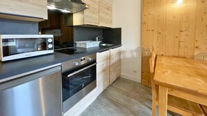A modern kitchen with wooden cabinets, a stainless steel oven, a microwave, and a wooden dining table.