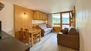 A cozy room with a wooden dining table, chairs, a sofa, and a couch. There's a window with a view of the outdoors.