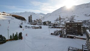 A snow-covered ski resort with buildings, ski lifts, and a mountainous backdrop.