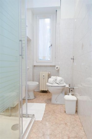 Un baño pequeño con inodoro, bidé y cabina de ducha de vidrio.