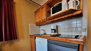 Una cocina compacta con lavavajillas, microondas y cafetera sobre la encimera.