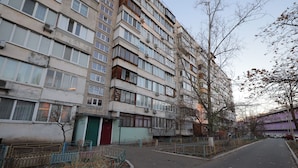 A multi-story residential building with a flat facade, large windows, and a gated entrance.
