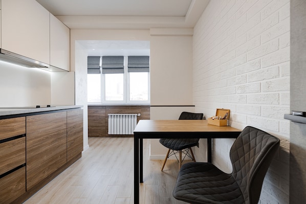 A modern kitchen with wooden cabinets, a black countertop, and a dining area with a table and chairs.