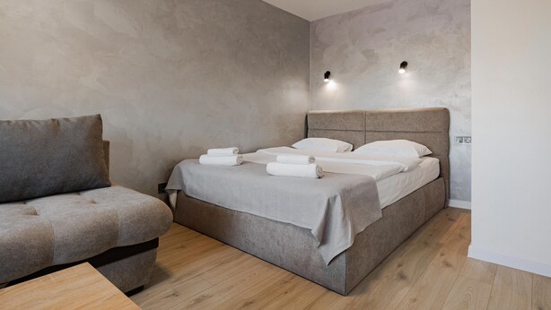 A modern bedroom with a bed, a sofa, and a small table.