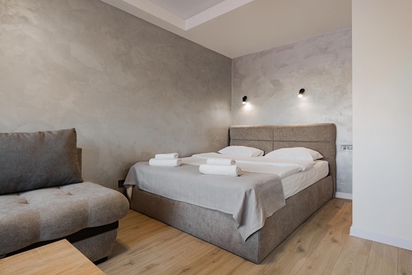 A modern bedroom with a bed, a sofa, and a small table.