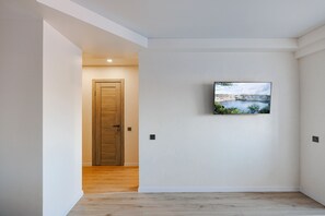 A hallway with a wooden door, a mounted TV, and a view of a lake through a window.
