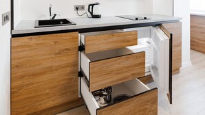 A modern kitchen with white cabinetry, a black countertop, and wooden drawer fronts.