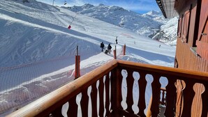 Een skipiste met een houten balkonhek dat uitzicht biedt op de omgeving.
