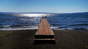 A wooden pier extending into calm waters with a clear sky above. - Azzurro Camping Village (Bracciano)