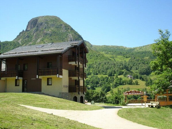 A multi-story building with balconies, a sign for a bar/restaurant, and a mountain in the background. - 2 rooms for 4 pers. across cable car St Martin de Belleville, pets allowed (Saint-Martin-de-Belleville-Les Menuires)