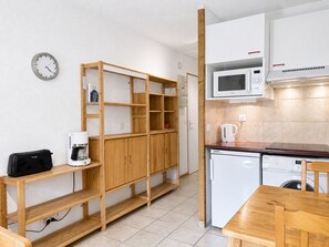 A compact kitchen with a microwave, coffee maker, and a wooden cabinet structure.