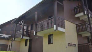 A multi-story building with balconies, a sign indicating 'Les Gentianes', and a clear sky.