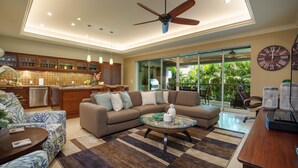 A spacious living area with a large sofa, a coffee table, and a ceiling fan.