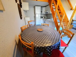 A dining area with a round table covered in a polka dot tablecloth, surrounded by wooden chairs. - Economical apartment with mezzanine for 6 people in Les Menuires (Les Menuires)