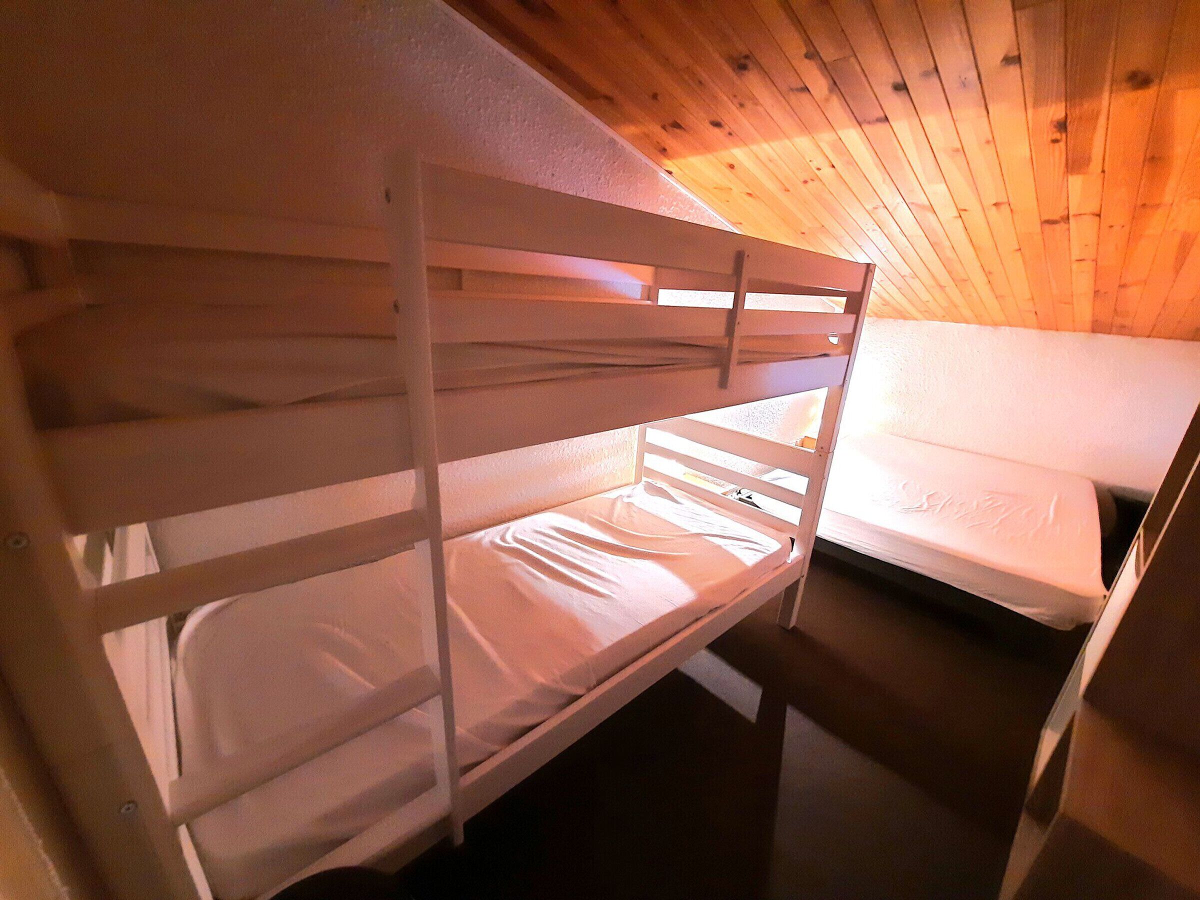 Un lit superposé dans une pièce aux murs en bois et au plafond en pente.