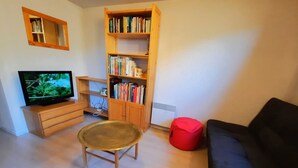 A living room with a television, a bookshelf, a red bean bag, and a black sofa. - Economical apartment with mezzanine for 6 people in Les Menuires (Les Menuires)