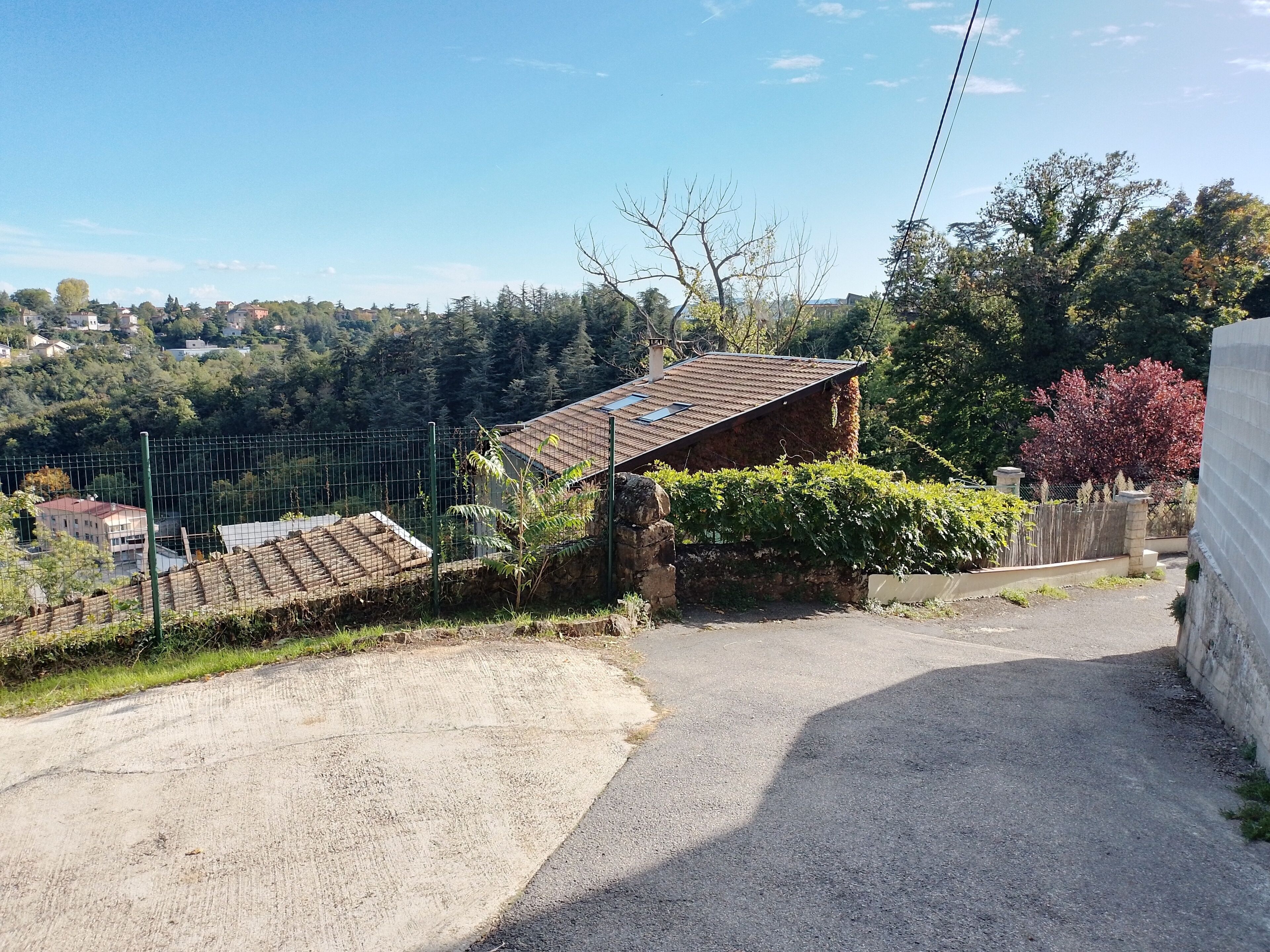 Uma estrada rural com uma pequena casa de pedra e uma área cercada.