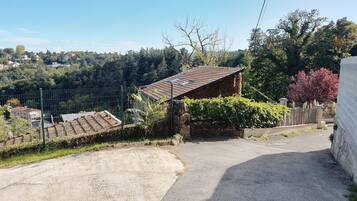Uma estrada rural com uma pequena casa de pedra e uma área cercada.