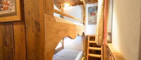 Una cama litera de madera con escalera, una ventana pequeña y un cartel en la pared.