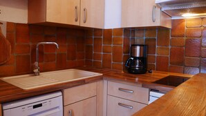 A compact kitchen with a sink, a coffee maker, and a dishwasher.
