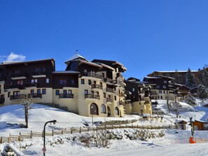Ein schneebedecktes Skigebiet mit mehrstöckigen Gebäuden, Balkonen und Skiliften.