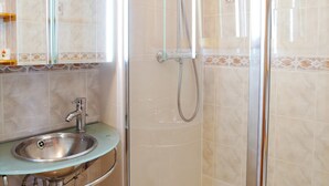 A bathroom with a sink, mirror, and shower.