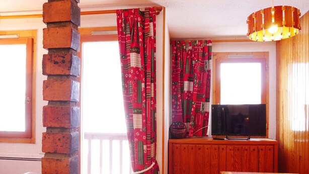 A cozy room with a wooden bench, a television on a wooden cabinet, and a brick wall.