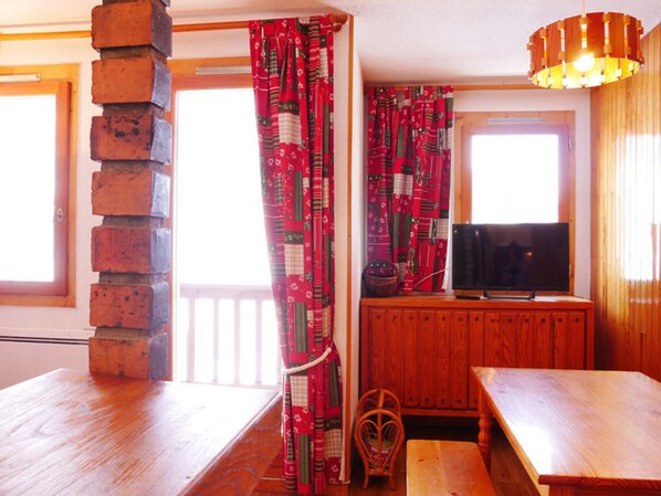 Una habitación acogedora con un banco de madera, un televisor sobre un mueble de madera y una pared de ladrillo.