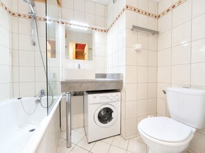 A bathroom with a bathtub, a washing machine, and a toilet. - Cozy Studio for Couples, Ski-In/Ski-Out Access, Central Les Menuires (Les Menuires)