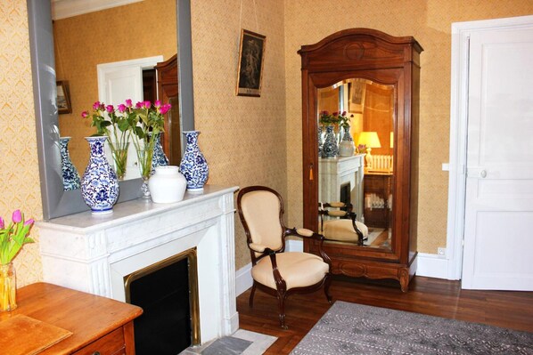 A room with a fireplace, a mirror, and a chair. - Château du Gerfaut (Azay-le-Rideau)