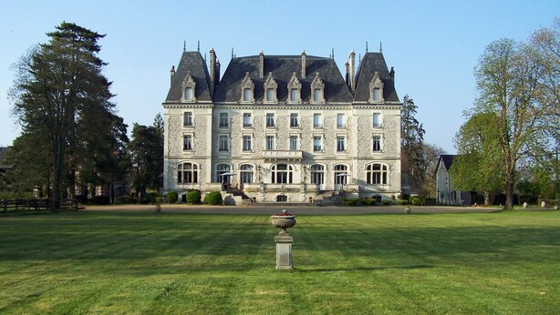A large stone building with multiple windows and a symmetrical facade, surrounded by a well-maintained lawn and trees. - Château du Gerfaut (Azay-le-Rideau)