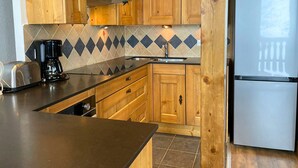 A kitchen with wooden cabinets, a stainless steel refrigerator, a coffee maker, and a toaster.